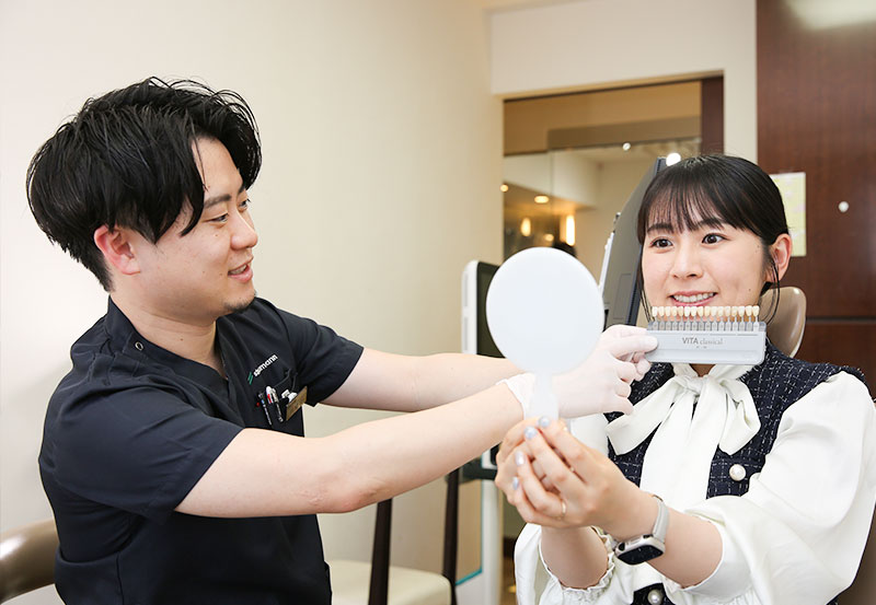 歯の白さを確認する歯科医師