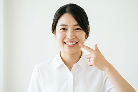 自分の歯を指さす女性