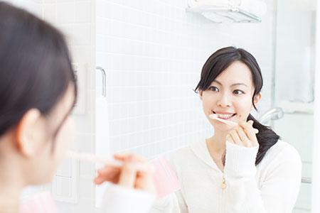 鏡を見ながら歯を磨く女性