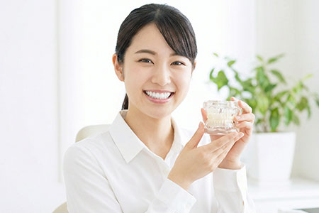 歯の模型を持って微笑む女性