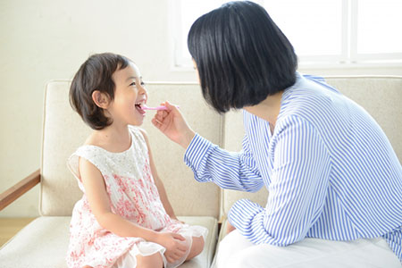 子供に仕上げ磨きをする母親