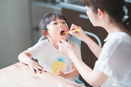 子供の仕上げ磨きを行う母親