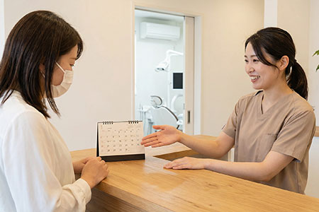 歯科医院で来院日を相談する歯科スタッフ