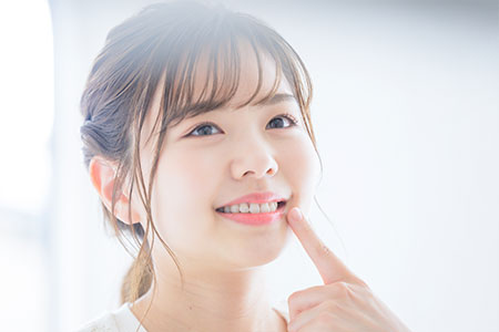 白い歯を指さす女性
