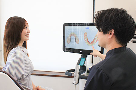 モニターで歯並びの様子を説明する歯科医師