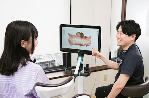 モニターを使って患者さんに説明する歯科医師